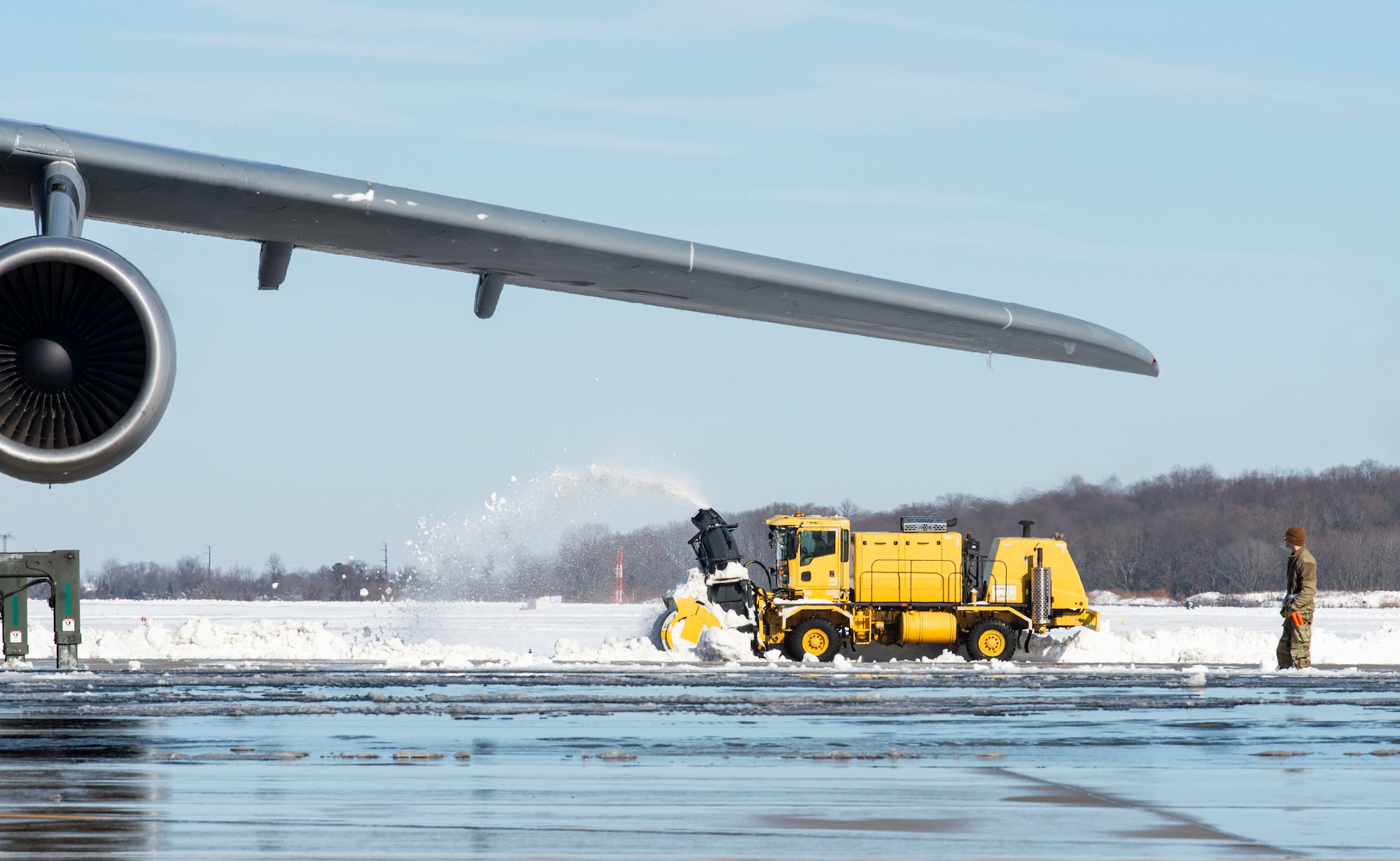 A 436th Civil Engineer Squadron member clears snow off a taxiway at Dover Air Force Base, Delaware, Jan. 4, 2022. Snow removal crews worked around the clock to remove eight inches of snow and ice from Winter Storm Frida that accumulated on the two runways and numerous taxiways. (U.S. Air Force photo by Roland Balik)