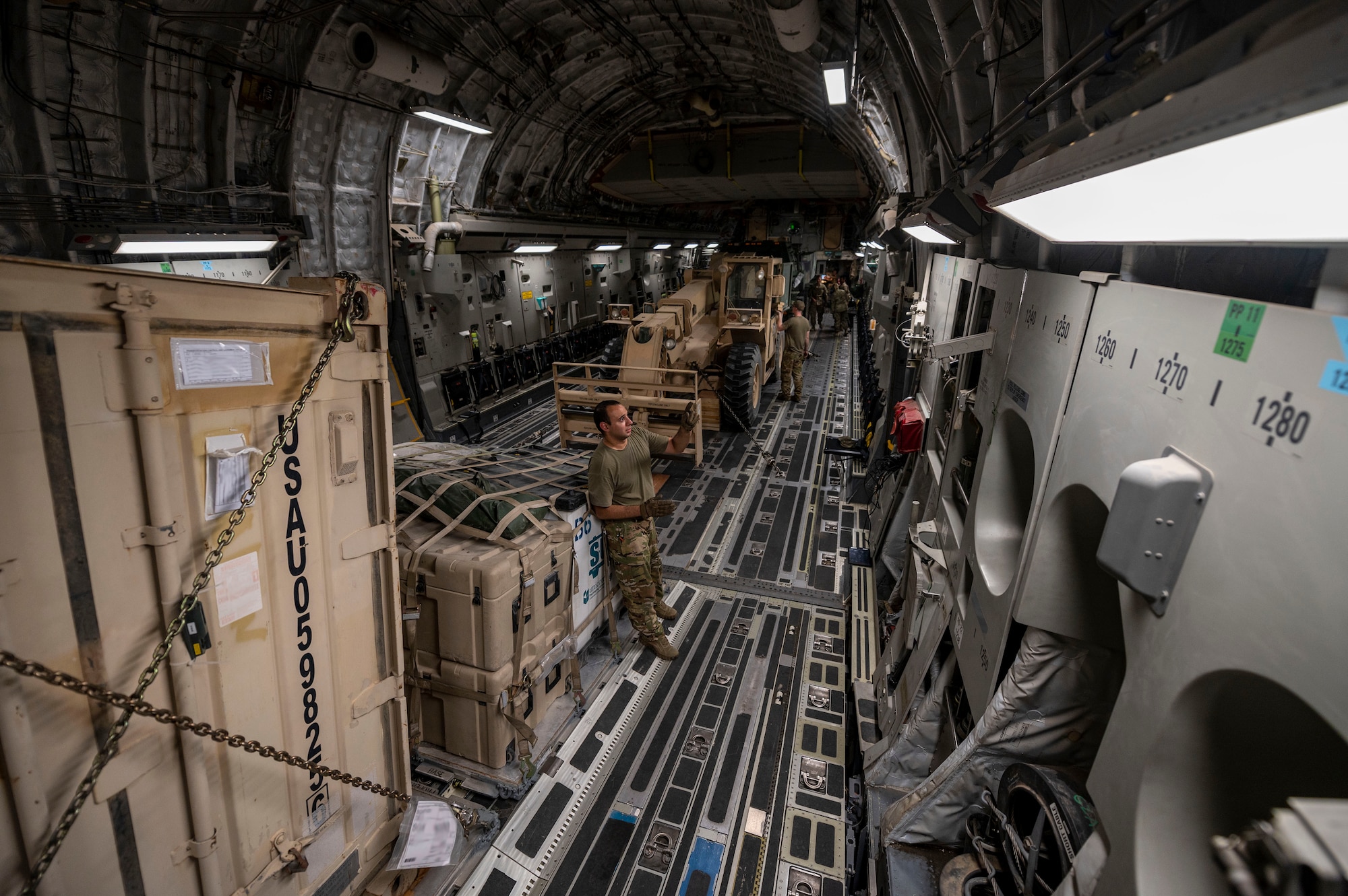 A U.S. Air Force C-17 Globemaster III aircraft loadmaster, assigned to the 816th Expeditionary Airlift Squadron, ensures the cargo is secured properly during a mission in support of Combined Joint Task Force - Operation Inherent Resolve in the U.S. Central Command area of responsibility, Aug. 14, 2021. U.S. Air Force photo illustration by Senior Airman Taylor Crul)