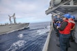 Sailors fire a line from Arleigh Burke-class guided missile destroyer USS Benfold to the Japanese Maritime Self-Defense Force Towada-class replenishment oiler ship JS Towada, during a replenishment-at-sea in the Philippine Sea, Dec. 23, 2021.