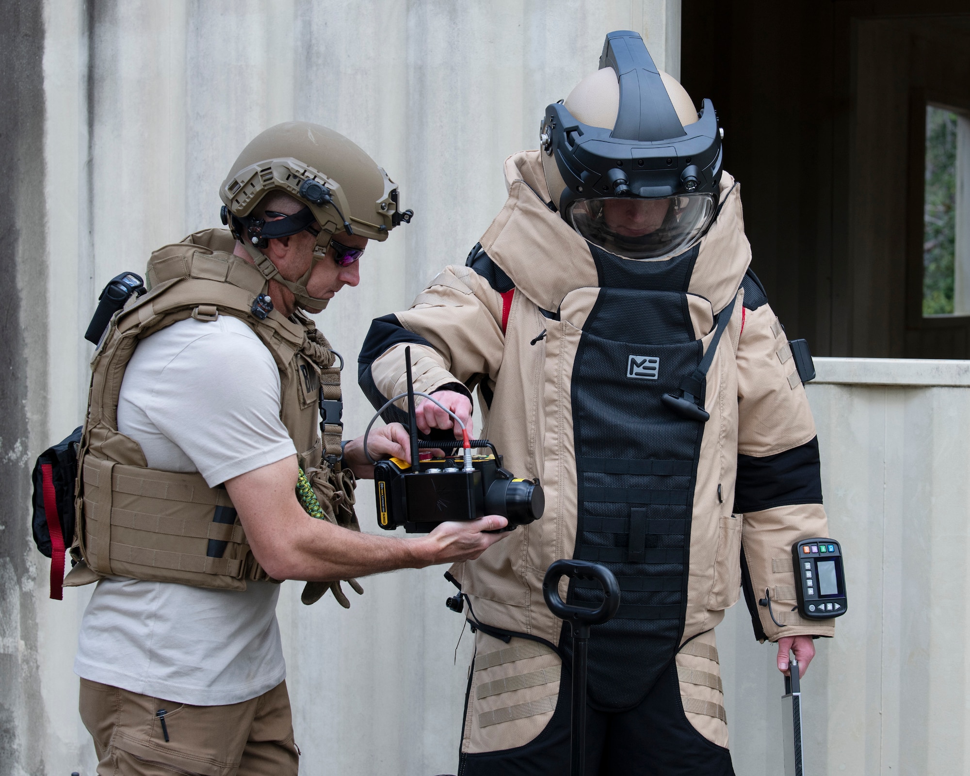 A Florida State Bomb Squad EOD tech hands a 919th Special Operations Civil Engineer Squadron  EOD tech an X-ray device during an IED training scenario.