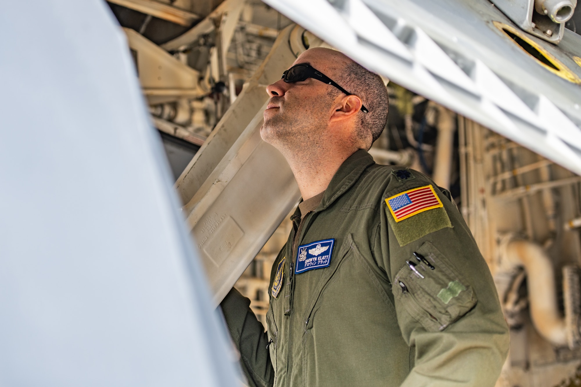 A pilot performs a preflight check underneath the wing of a plane