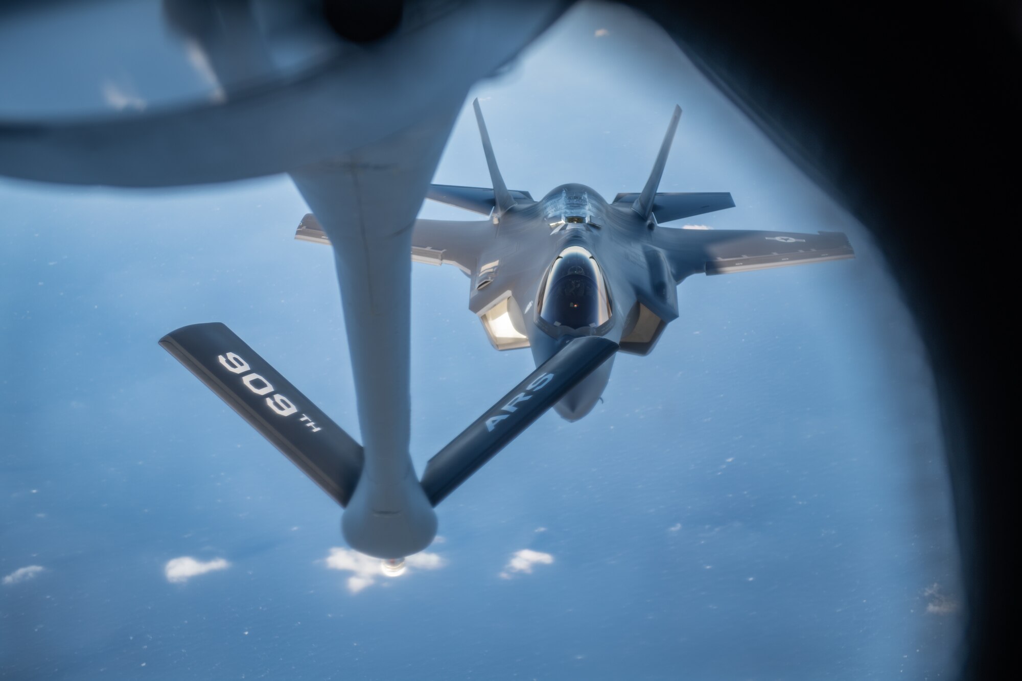 A jet approaches a refueling plane midair