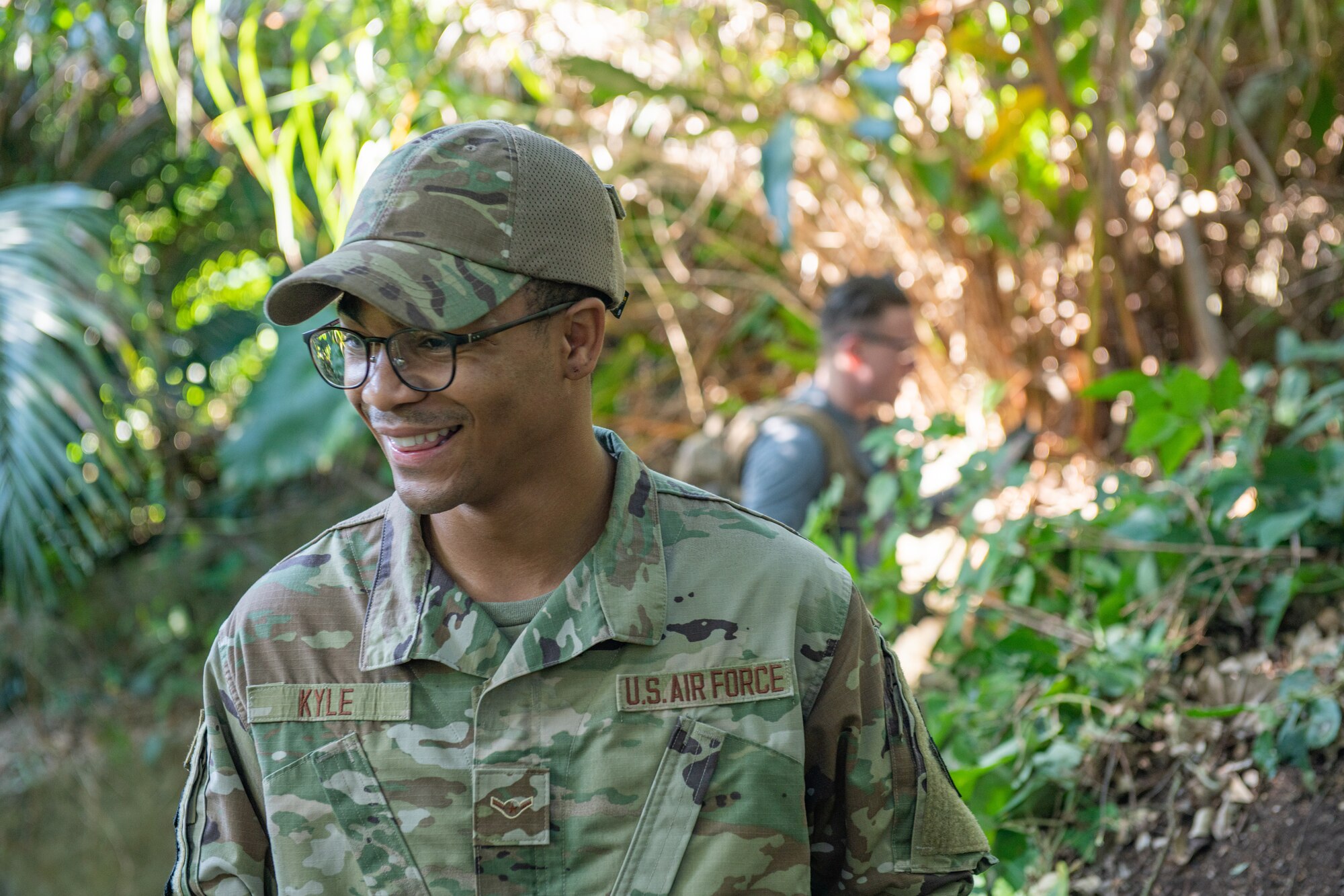 An Airman smiles as he clears vegetation from a shrine