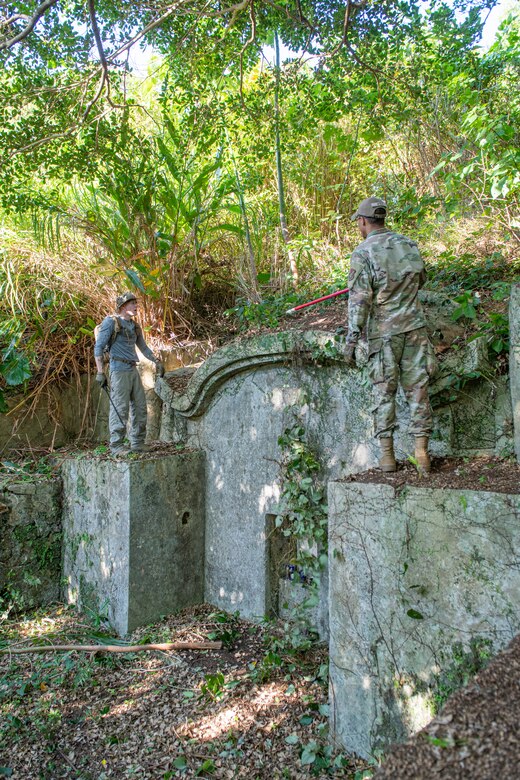 Two Airmen talk to each other next to a shrine