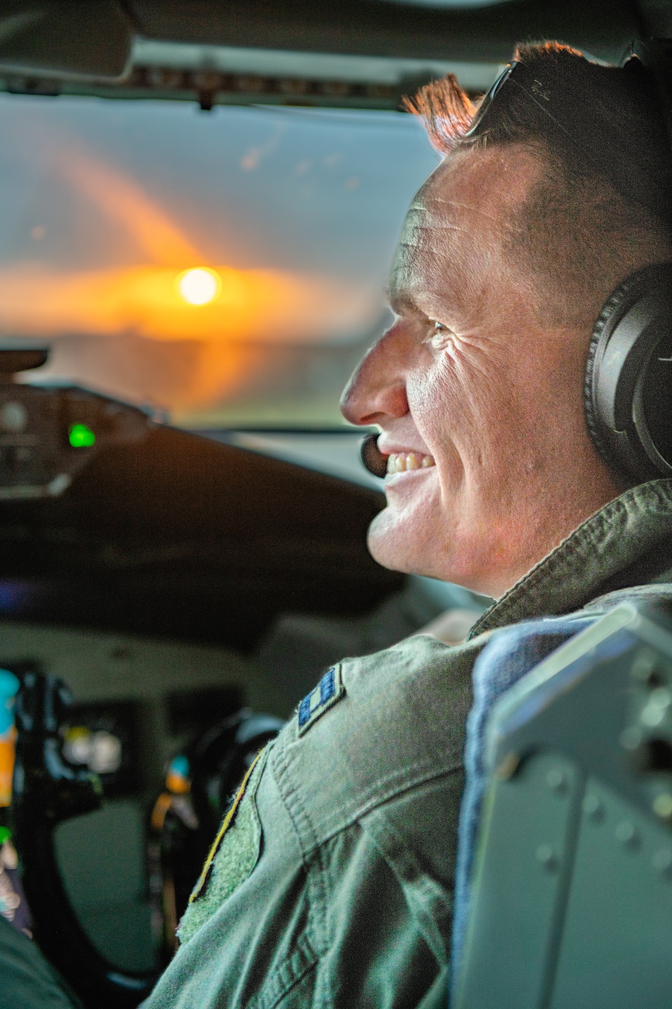 A pilot smiles at his copilot as the sunsets out the window of the cockpit