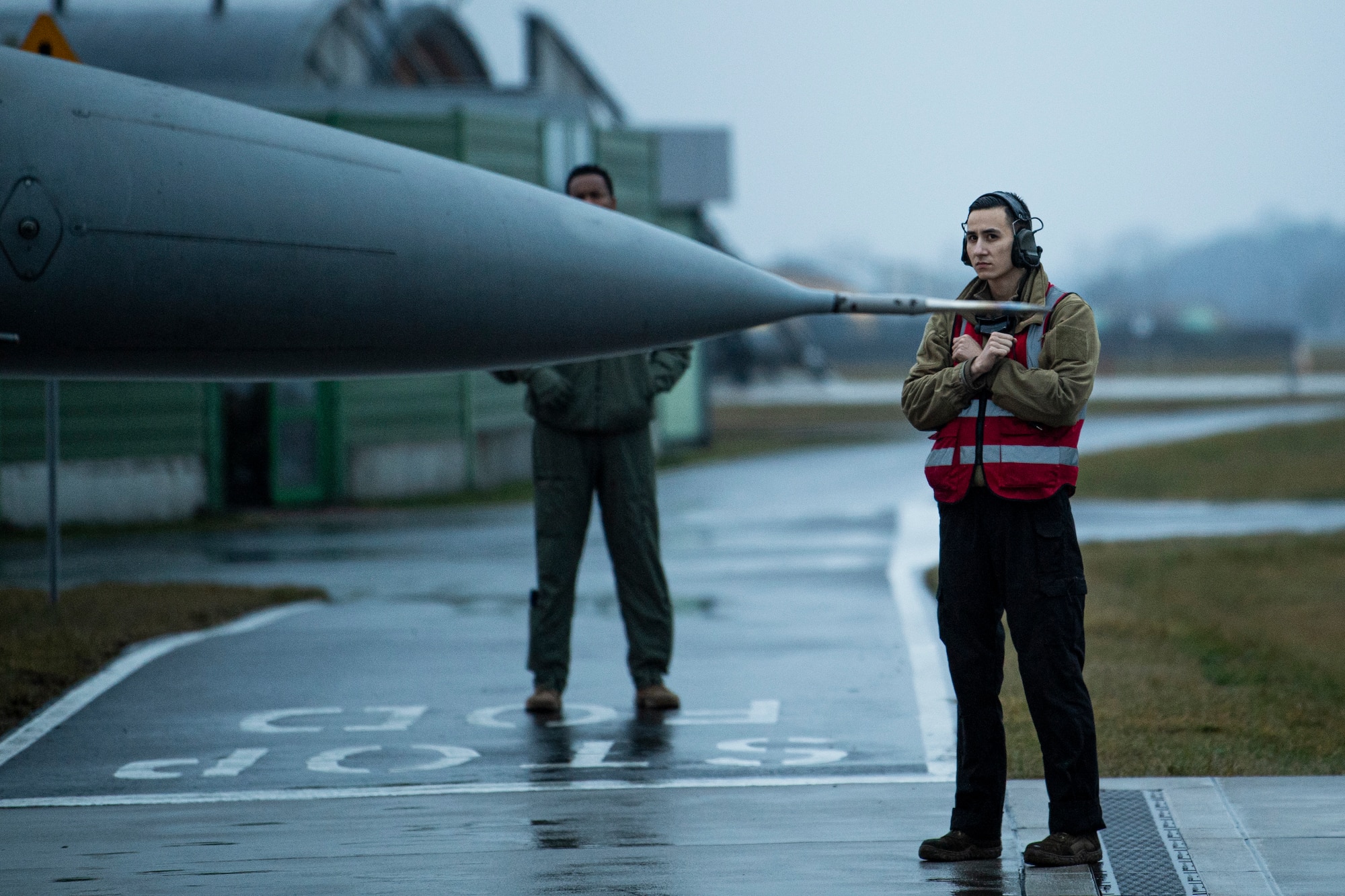 A U.S. Air Force F-16 Fighting Falcon crew chief assigned to the 480th Fighter Squadron at Spangdahlem Air Base, Germany, marshalls an aircraft at Łask Air Base, Poland, January 4, 2022.