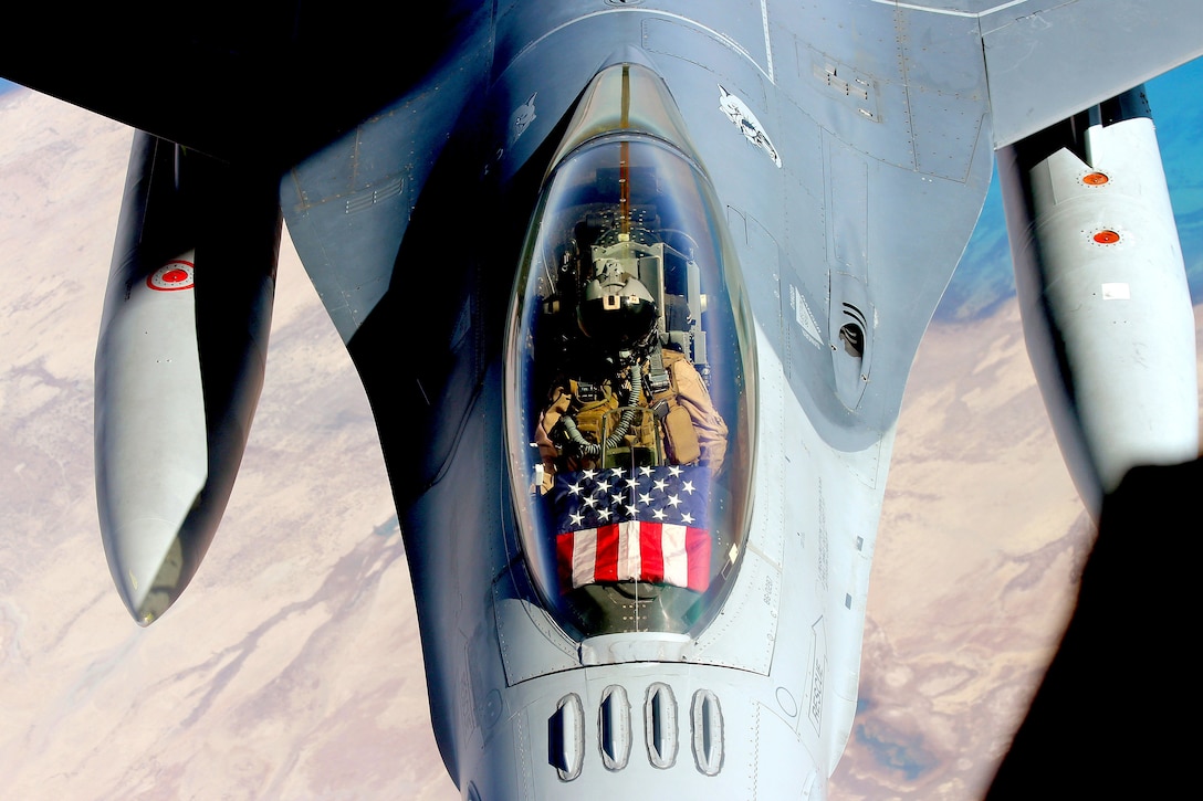 The American flag is seen from above in the cockpit of a fighter jet.