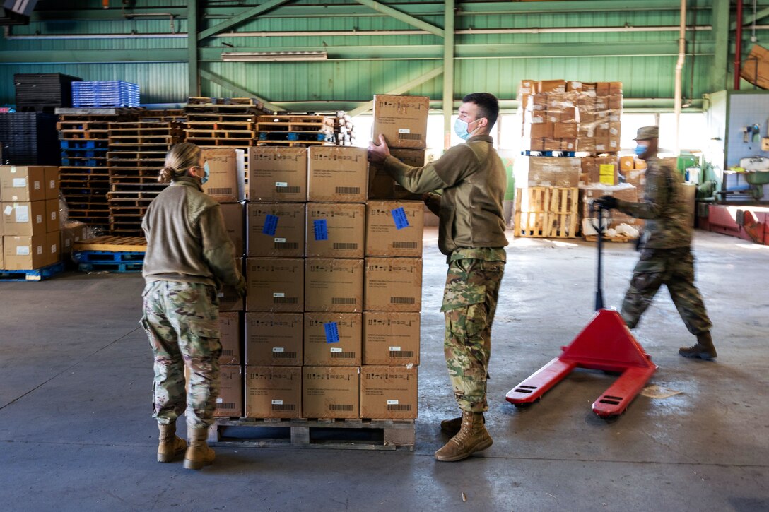 National Guardsmen organize boxes of rapid COVID-19 test kits.