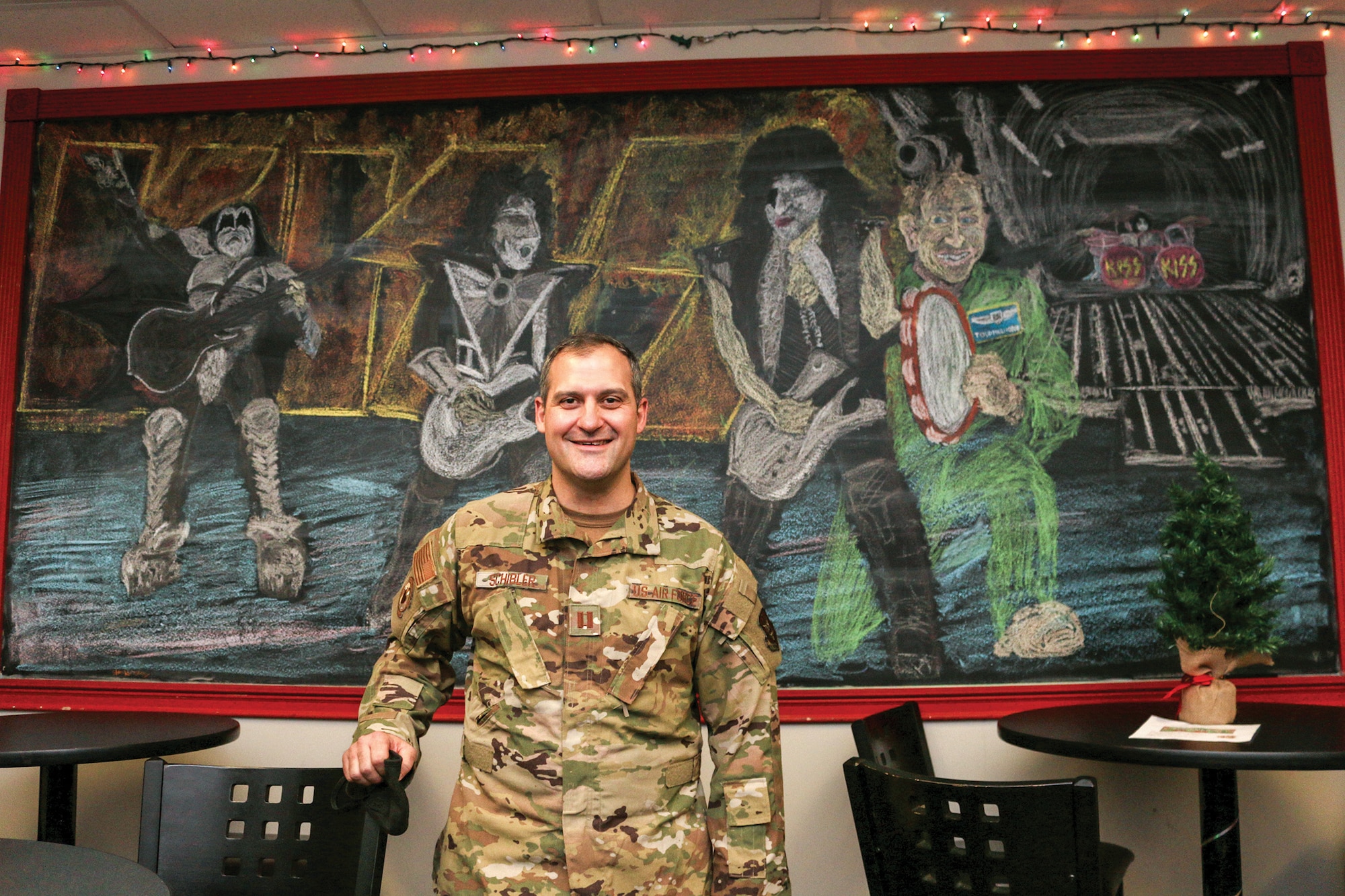 Capt. Michael Schibler, a flight nurse for the 445th Aeromedical Evacuation Squadron, poses in front of his chalk illustration of the rock band, KISS, Dec. 5, 2021.