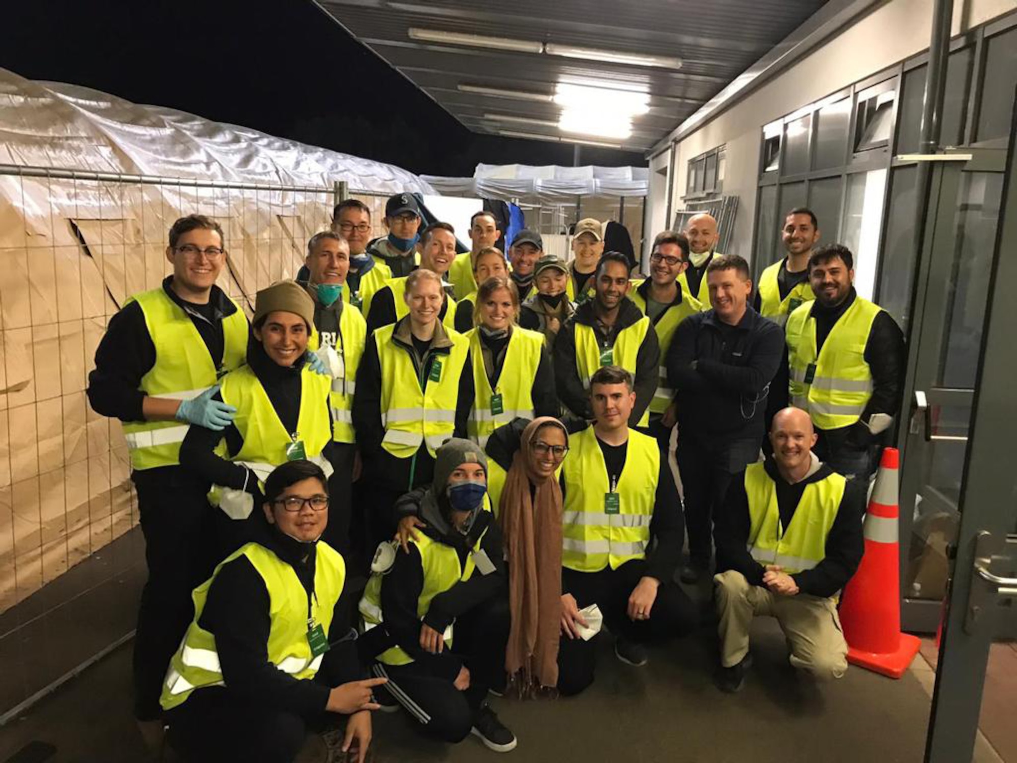 Group of men and women in bright yellow vests standing and crouching down while posing for a photo.