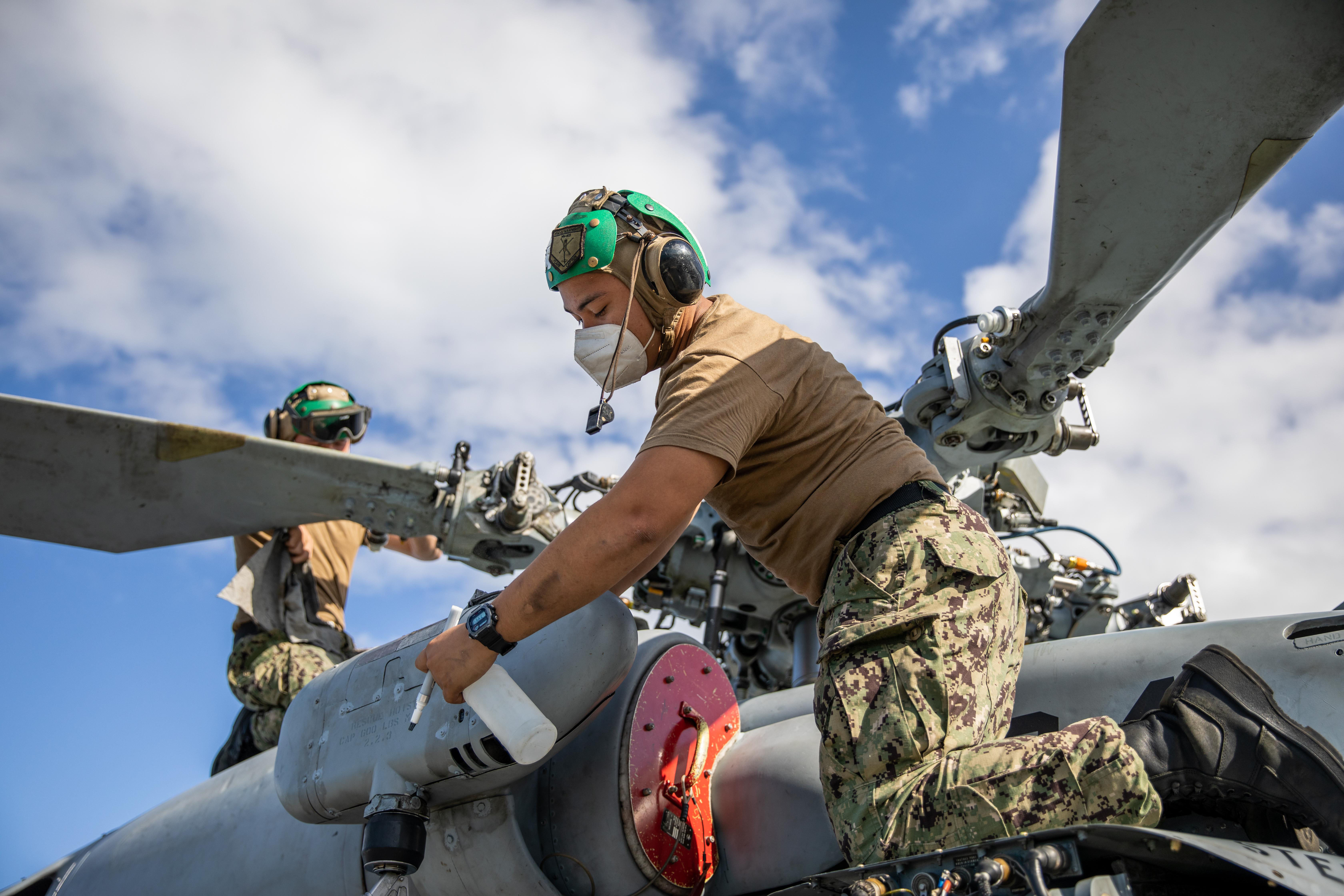 Aviation Machinist’s Mate Airman Felix Ricoospina and Aviation Machinist’s Mate 3rd Class Daimein Day, assigned to the “Sea Knights” of Helicopter Sea Combat Squadron (HSC) 22, Detachment 5, clean the blades of an MH-60S Sea Hawk helicopter on the flight deck of the Freedom-variant littoral combat ship USS Milwaukee (LCS 5).