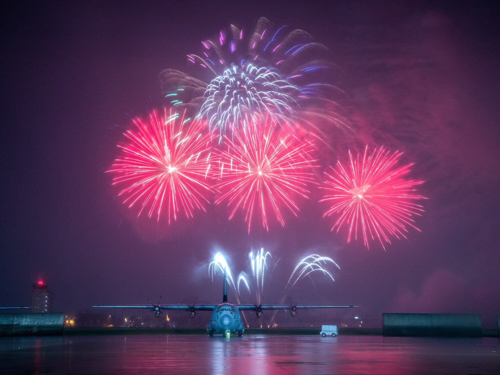 Fireworks explode behind a C-130J Super Hercules