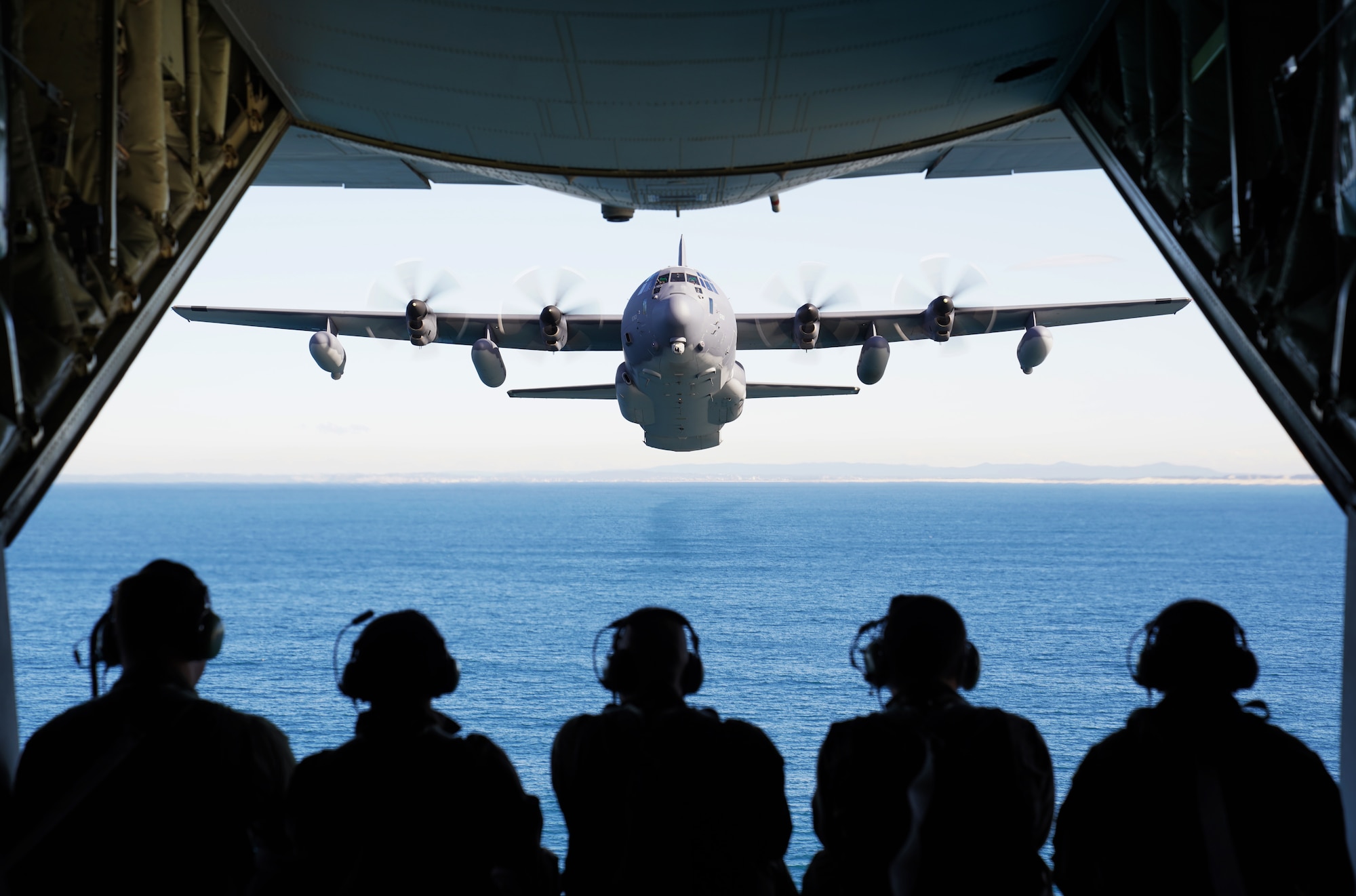 U.S. and Royal Australian Air Force Airmen observe an MC-130J Air Commando II flying