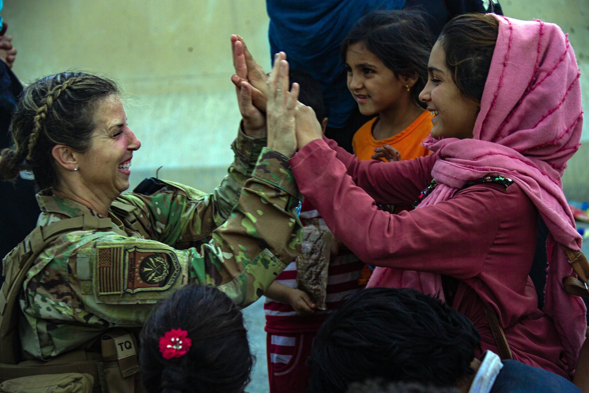 A U.S. Airman with Joint Task Force-Crisis Response high-fives a child after helping reunite their family