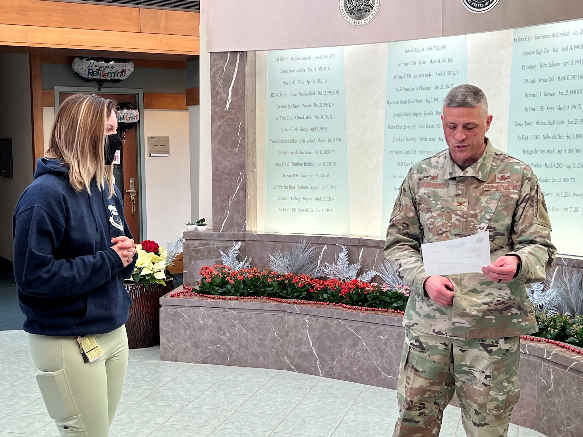 Staff Sgt. Alyssa Day, Air Force Mortuary Affairs Operations public affairs specialist, listens as Col. Chip Hollinger, AFMAO commander, reads a memorandum announcing her selection for the Dec. 25, 2021 in the AFMAO atrium notifying her selection as a Fiscal Year 2022 Senior Leader Enlisted Commissioning Program-Active Duty Scholarship recipient. Day will attend Arizona State University, and upon finishing her degree will attend Officer Training School. (U.S. Air Force photo by Christin Michaud)