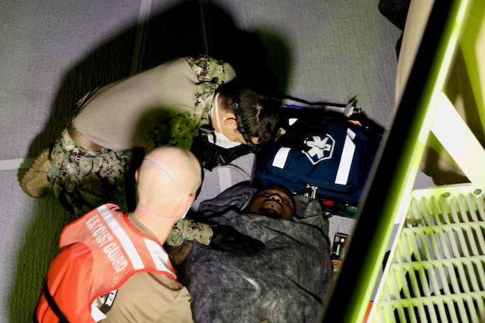 Petty Officer 3rd Class Christian Ortega Santiago, a hospital corpsman, and another member of the crew of the Sentinel-class USCGC Glen Harris (WPC 1145) treat a migrant for symptoms of hypothermia following his rescue from the water in the Atlantic Ocean Jan. 5, 2021.