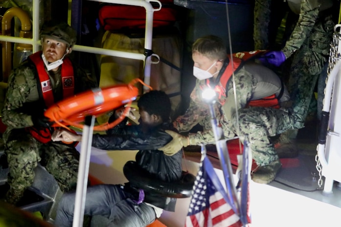 The crew of the Sentinel-class USCGC Glen Harris (WPC 1145) help migrants rescued from the water aboard the cutter in the Atlantic Ocean Jan. 5, 2021.
