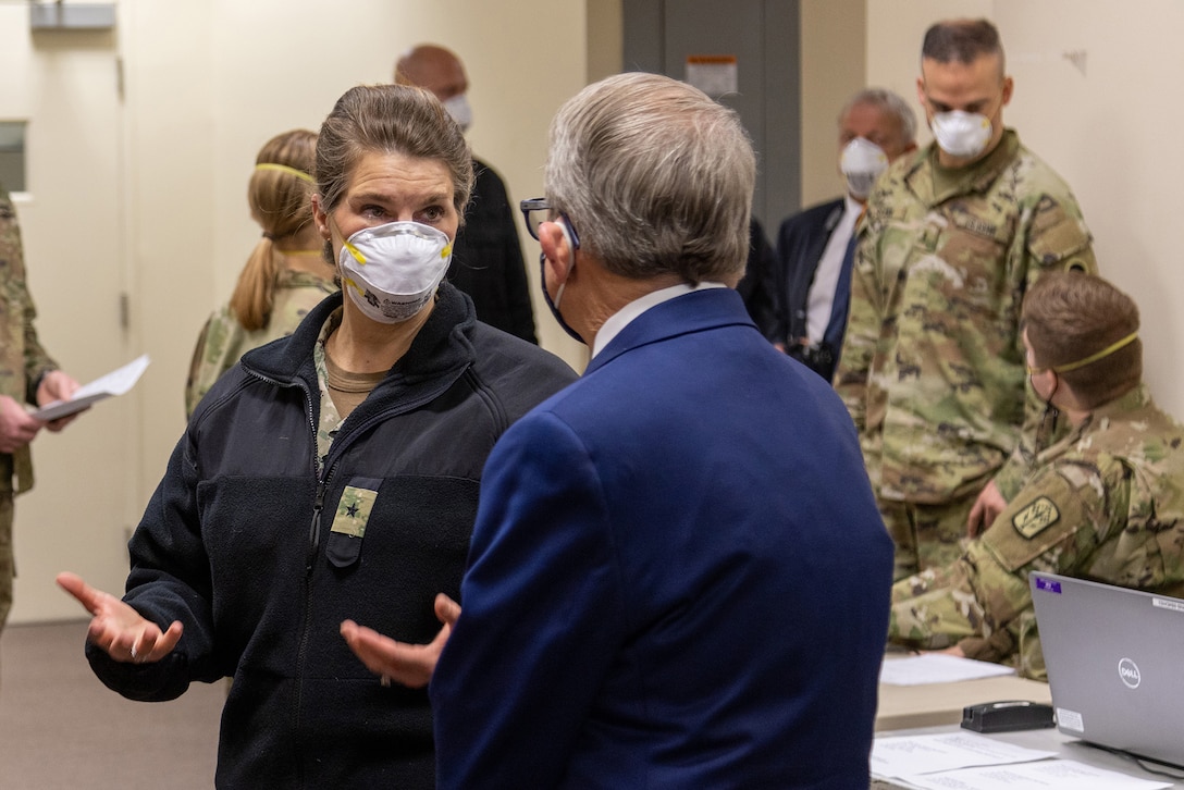 Commander Fabry in a Navy utility uniform meets with Ohio Gov. Mike DeWine in a dark blue suit.