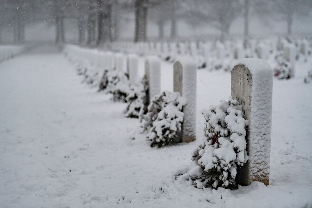 Snow falls on a tombstone.
