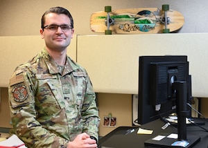 An Airman stands in front of his desk