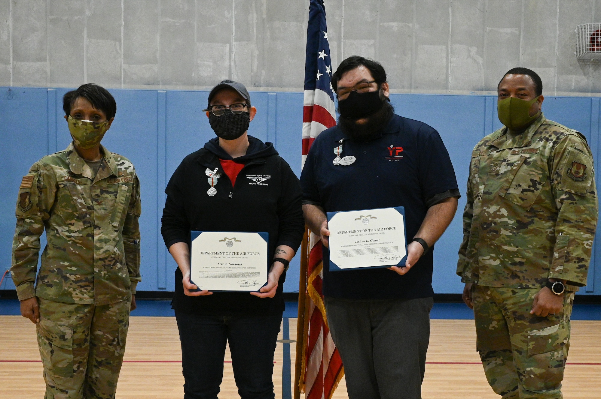 From left: Col. Jenise Carroll, 75th Air Base Wing commander, Nowinksi, Gomez, and Chief Master Sgt. Raymond Riley, 75th ABW command chief posing for a photo. Nowinski and Gomez are holding their certificates and have the Award for Valor medals pinned to their chests.