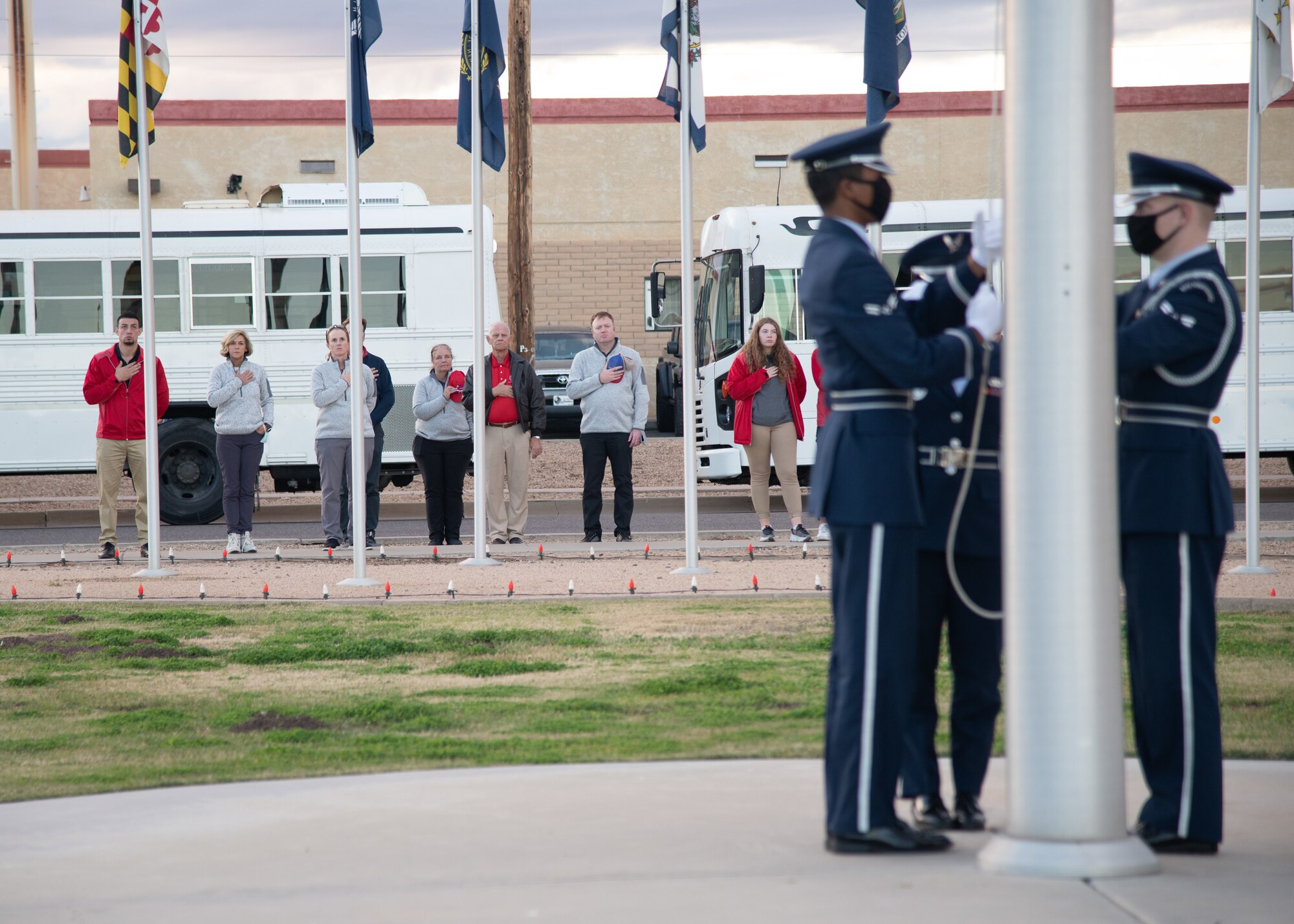 Patriot All-American golf tournament members place their right hand over their hearts during an honor guard ceremony Dec. 29, 2021, at Luke Air Force Base, Arizona. Every year, the Wigwam Resort in Litchfield Park hosts the Patriot All-American golf tournament in honor of fallen and severely wounded service members. Golfers received a base tour that included a 56th Security Forces Squadron working dog demonstration and an F-16 Fighting Falcon and F-35 Lightning II aircraft display to showcase the 56th Fighter Wing mission. (U.S. Air Force photo by Staff Sgt. Collette Brooks)