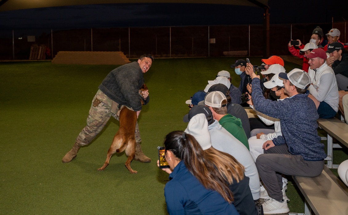 U.S. Air Force Tech. Sgt. Zackery Hons, 56th Security Forces Squadron military working dog handler, participates in a MWD demo during a base tour for Patriot All-American golf tournament participants Dec. 29, 2021, at Luke Air Force Base, Arizona. During the tour, 56th SFS members briefed golfers about the weapons and equipment they use and gave insight into what defenders do. (U.S. Air Force photo by Senior Airman Leala Marquez)