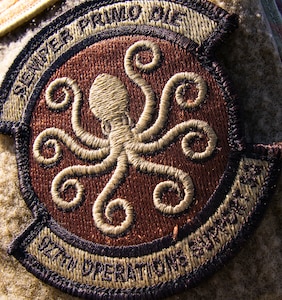The newly approved emblem of the 927th Operations Support Squadron is pictured in the configuration and color scheme for the Air Force Occupational Camouflage Pattern uniform. Illustrated within the patch is an eight-armed sea monster known as the kraken, as well as the Squadron’s motto “Semper Primo Die,” which is Latin for “Always the first day.” (U.S. Air Force photo by Tech Sgt. Bradley Tipton)