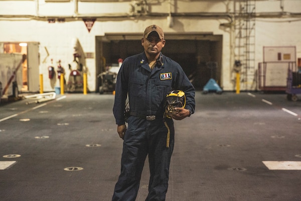 220105-M-AU949-0175 ARABIAN GULF (Jan. 5, 2022) – Aviation Boatswain’s Mate 1st Class Juan Troncoso poses for a photo in the bay hangar aboard the Expeditionary Sea Base USS Lewis B. Puller (ESB 3) Jan. 5. The Puller deployed to the U.S. 5th Fleet area of operations in support of naval operations to ensure maritime stability and security in the Central Region, connecting the Mediterranean and Pacific through the Western Indian Ocean and three strategic choke points. (U.S. Marine Corps photo by Staff Sgt. Victor A. Mancilla)