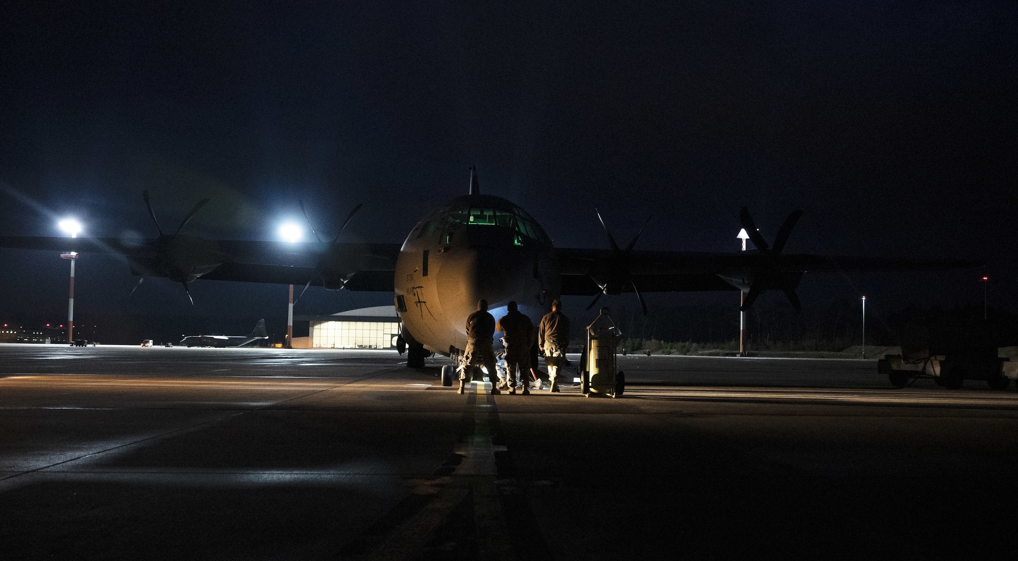 Airmen in front of an aircraft at night.