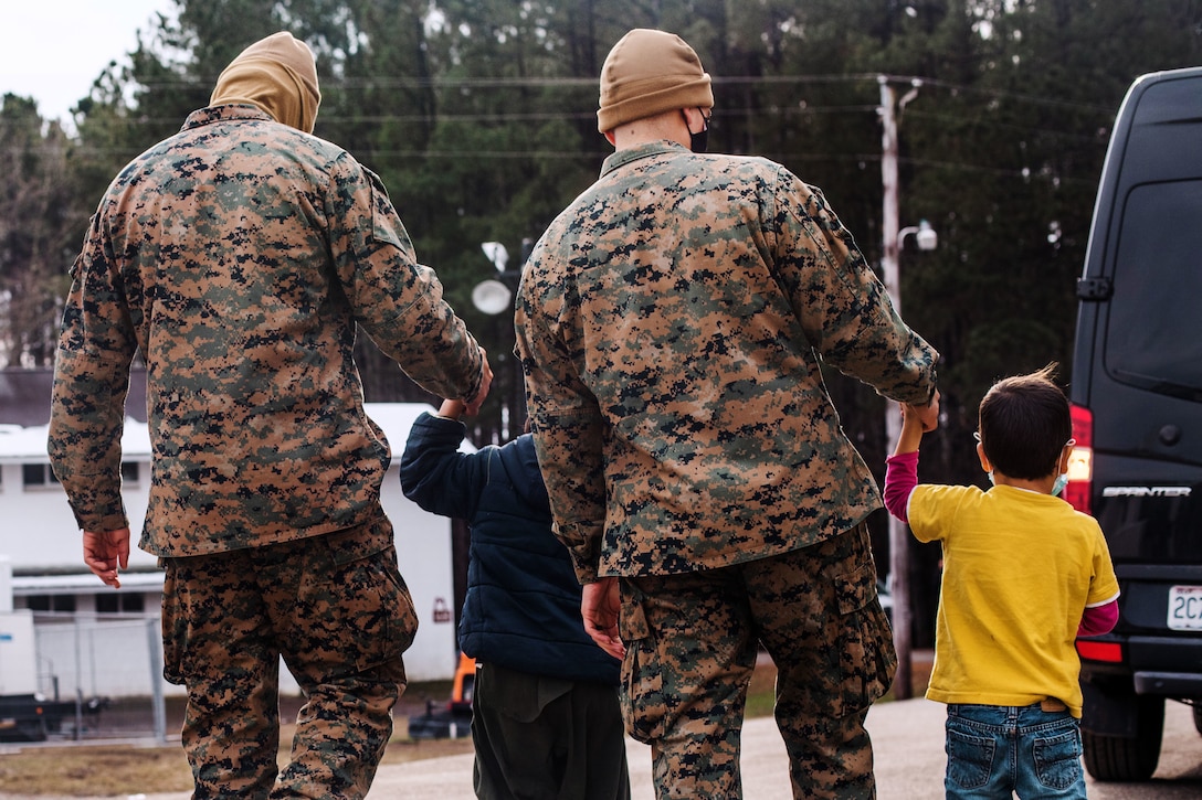 Afghan children walk with Marines.
