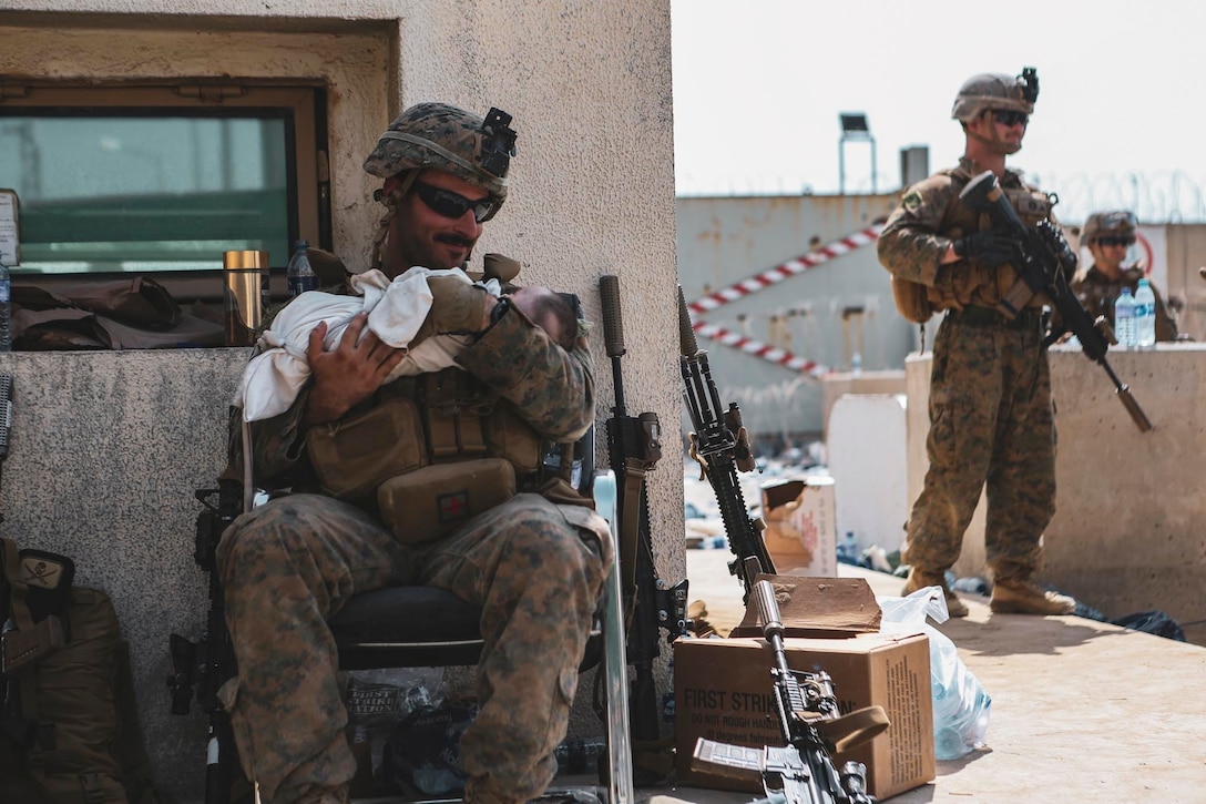 A Marine assigned to the 24th Marine Expeditionary Unit (MEU) calms an infant during an evacuation at Hamid Karzai International Airport, Kabul, Afghanistan, Aug. 20. U.S. service members and coalition partners are assisting the Department of State with a Non-combatant Evacuation Operation (NEO) in Afghanistan. (U.S. Marine Corps photo by Sgt. Isaiah Campbell)