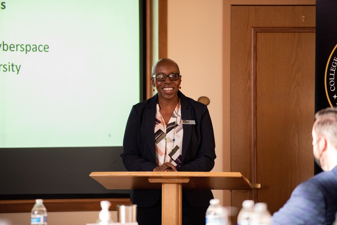 A woman standing behind a lectern speaks to a group.