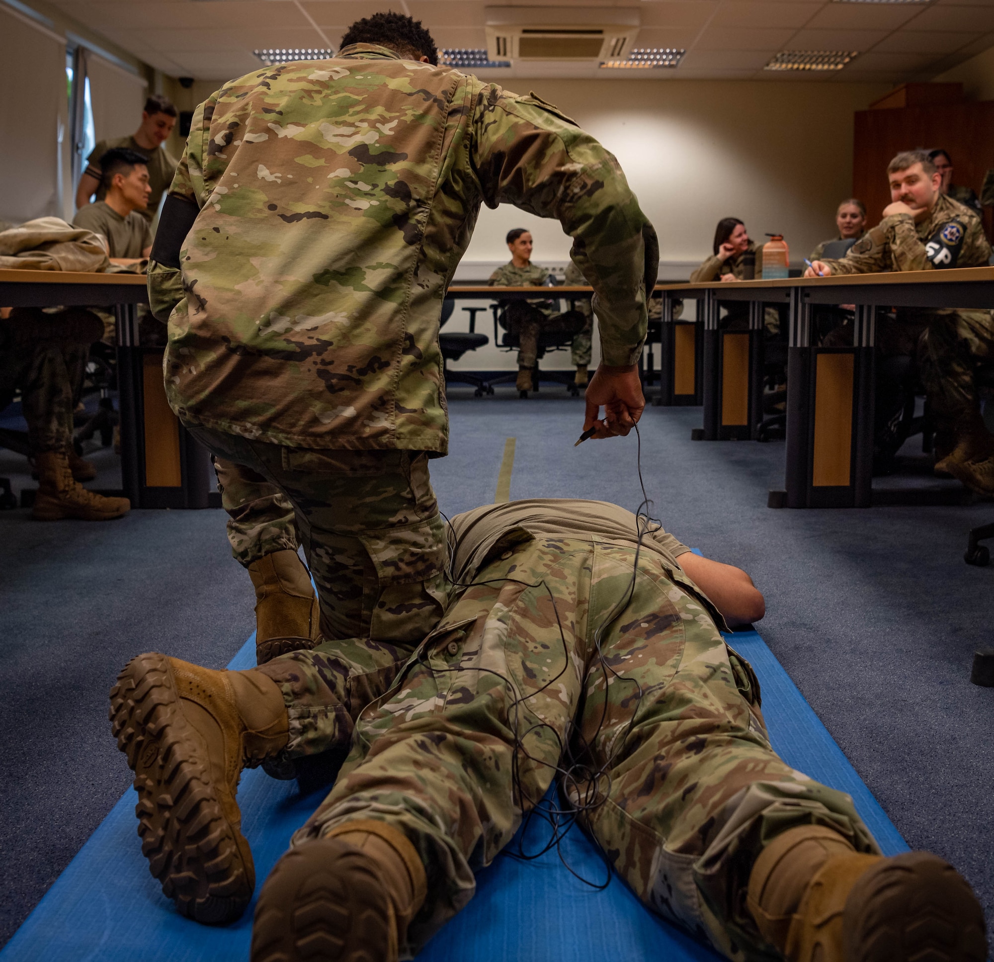 U.S. Air Force Staff Sgt. William Murray, left, 569th United States Forces Police Squadron unit training instructor, removes the probes of a Taser X26P from Senior Airman Andrew Alvarado, right, 86th Airlift Wing public affairs journeyman, at Vogelweh Air Station, Germany, Nov. 22, 2021. The Taser X26P uses a replaceable cartridge containing compressed nitrogen to deploy two small probes that are attached to the X26P energy weapon cartridge by insulated conductive wires with a maximum length of 15 feet. The two probes deliver Neuromuscular Incapacitation which occurs when an energy weapon is able to cause involuntary stimulation of both the sensory nerves and the motor nerves. (U.S. Air Force photo by Airman Jared Lovett)