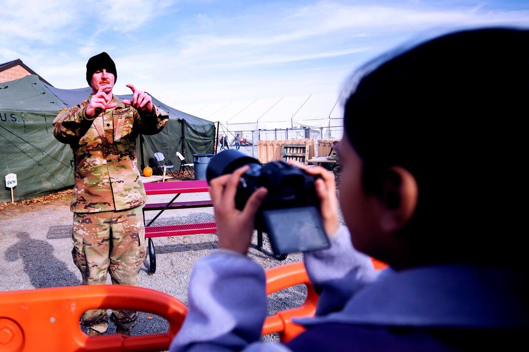 A soldier teaches an Afghan child how to use a camera.