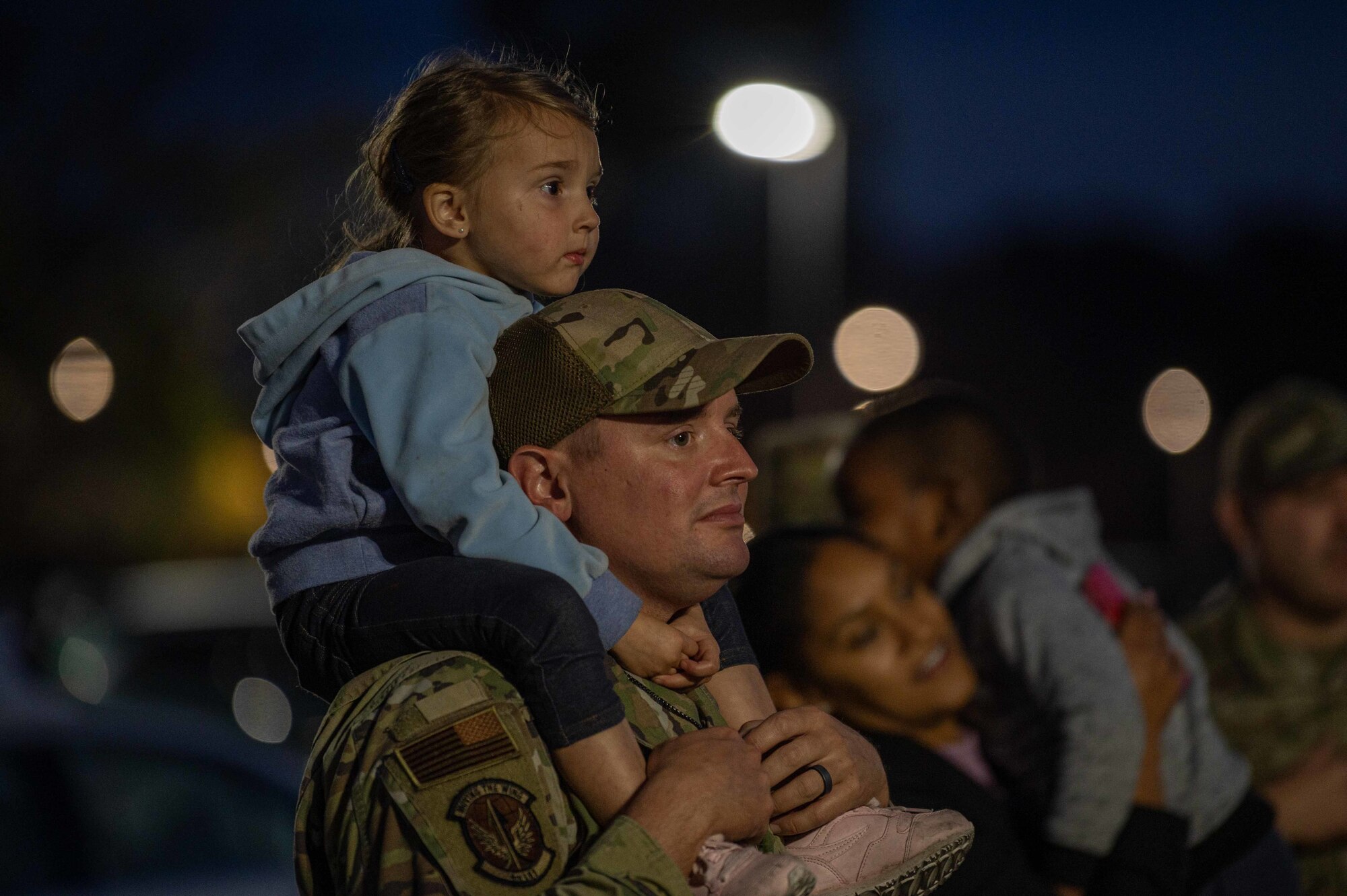 Air Force families watch Christmas carolers during a tree lighting ceremony at Seymour Johnson Air Force Base, North Carolina, Dec. 6, 2021. The tree lighting ceremony invited families across the base to participate in celebrating the holidays. (U.S. Air Force photo by Airman 1st Class Sabrina Fuller)