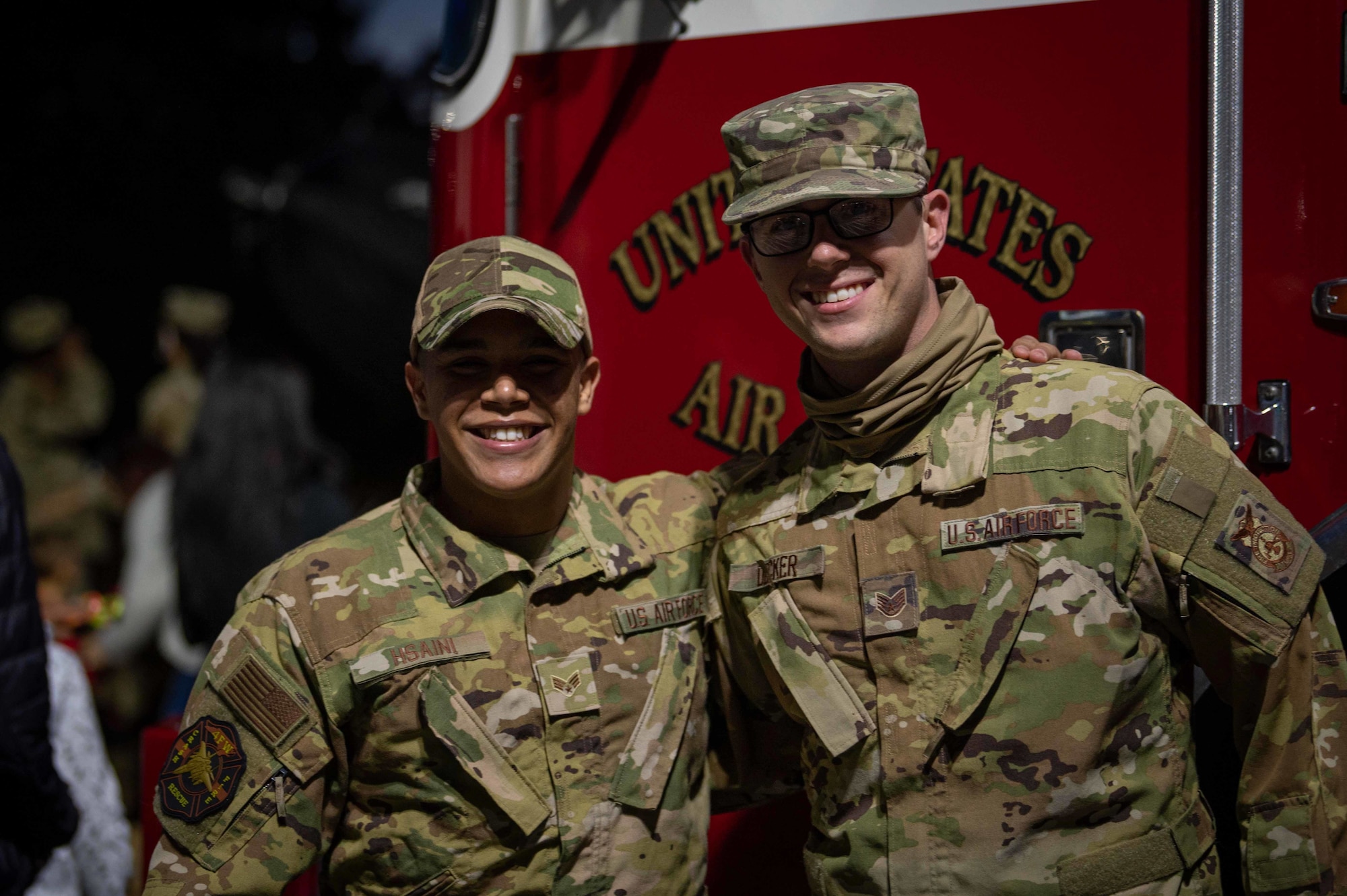 Staff Sgt. Andrew Decker, left, 4th Civil Engineering Squadron crew chief, and Senior Airman Marwane Hsaini, 4th Civil Engineering Squadron fire truck operator, pose in front of a fire truck at Seymour Johnson Air Force Base, North Carolina, Dec. 8, 2021. The fire department delivered Santa Claus to a tree lighting ceremony. (U.S. Air Force photo by Airman 1st Class Sabrina Fuller)