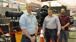 IMAGE: Naval Surface Warfare Center Dahlgren engineers (left to right) Matthew Buckler, Gregory Fish and Thomas Houck stand in front of the new 105mm Gun Aircraft Unit they helped develop for the AC-130 gunship.