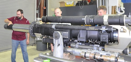 IMAGE: Naval Surface Warfare Center Dahlgren engineers (left to right) Thomas Houck, Matthew Buckler and Gregory Fish inspect the new 105mm Gun Aircraft Unit after testing. The weapon is specifically designed for the most lethal gunship, the AC-130J.