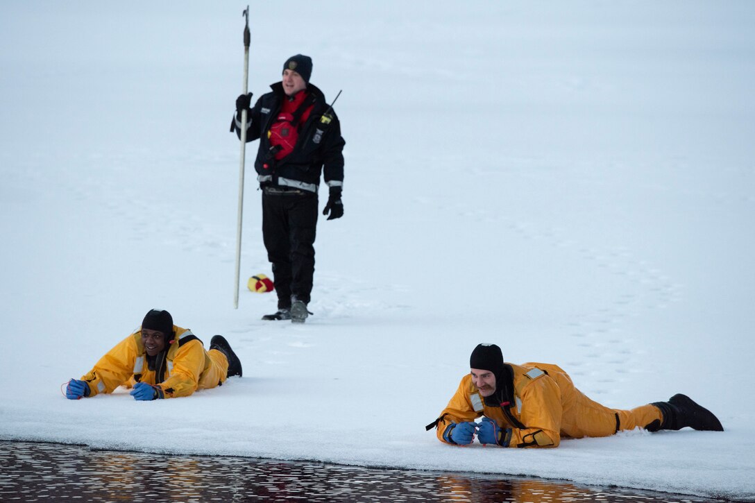 Airmen crawl across ice to open water.