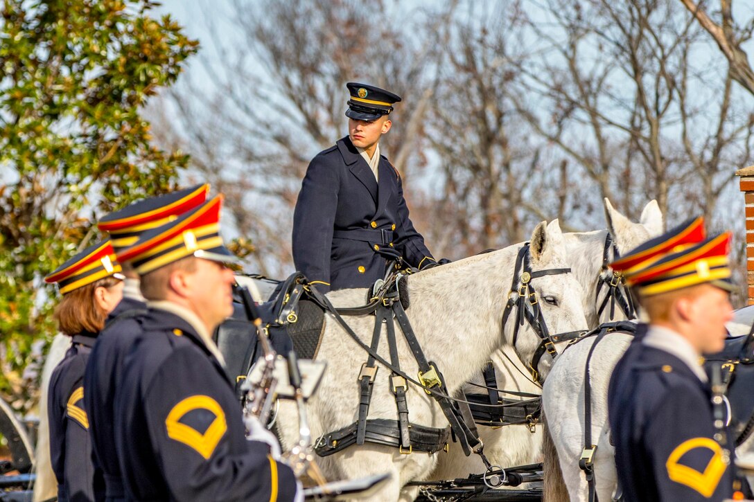 A soldier on a horse observes fellow soldiers as they march.