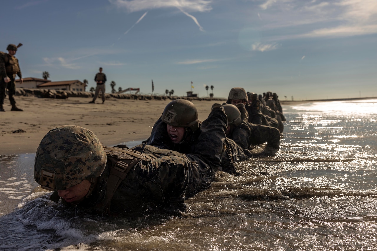 Marines conduct squad push-ups in the ocean surf.