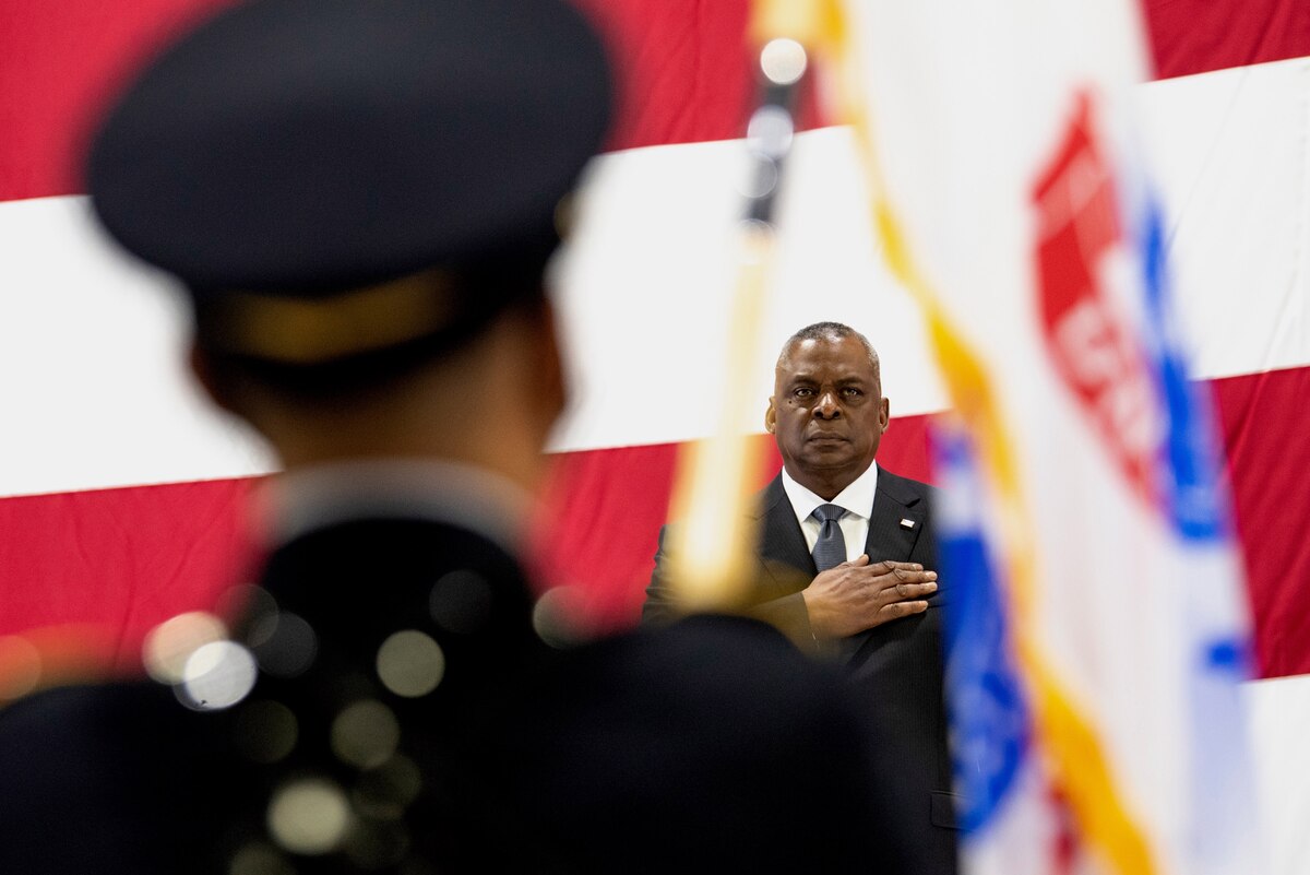 Secretary of Defense Lloyd J. Austin III speaks in front of a giant American flag. 