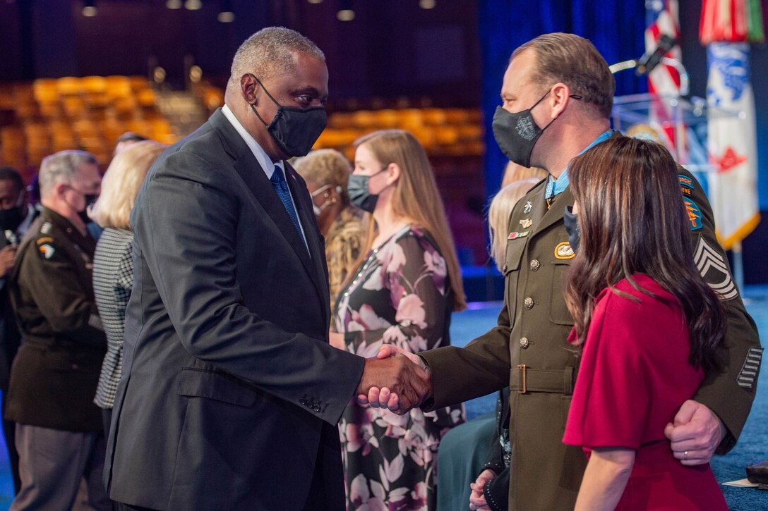 Secretary of Defense Lloyd J. Austin III shakes hands with a soldier wearing a Medal of Honor.