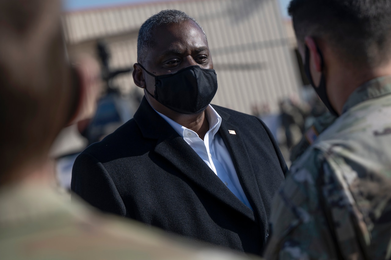 Secretary of Defense Lloyd J. Austin III stands outside and talks to troops.