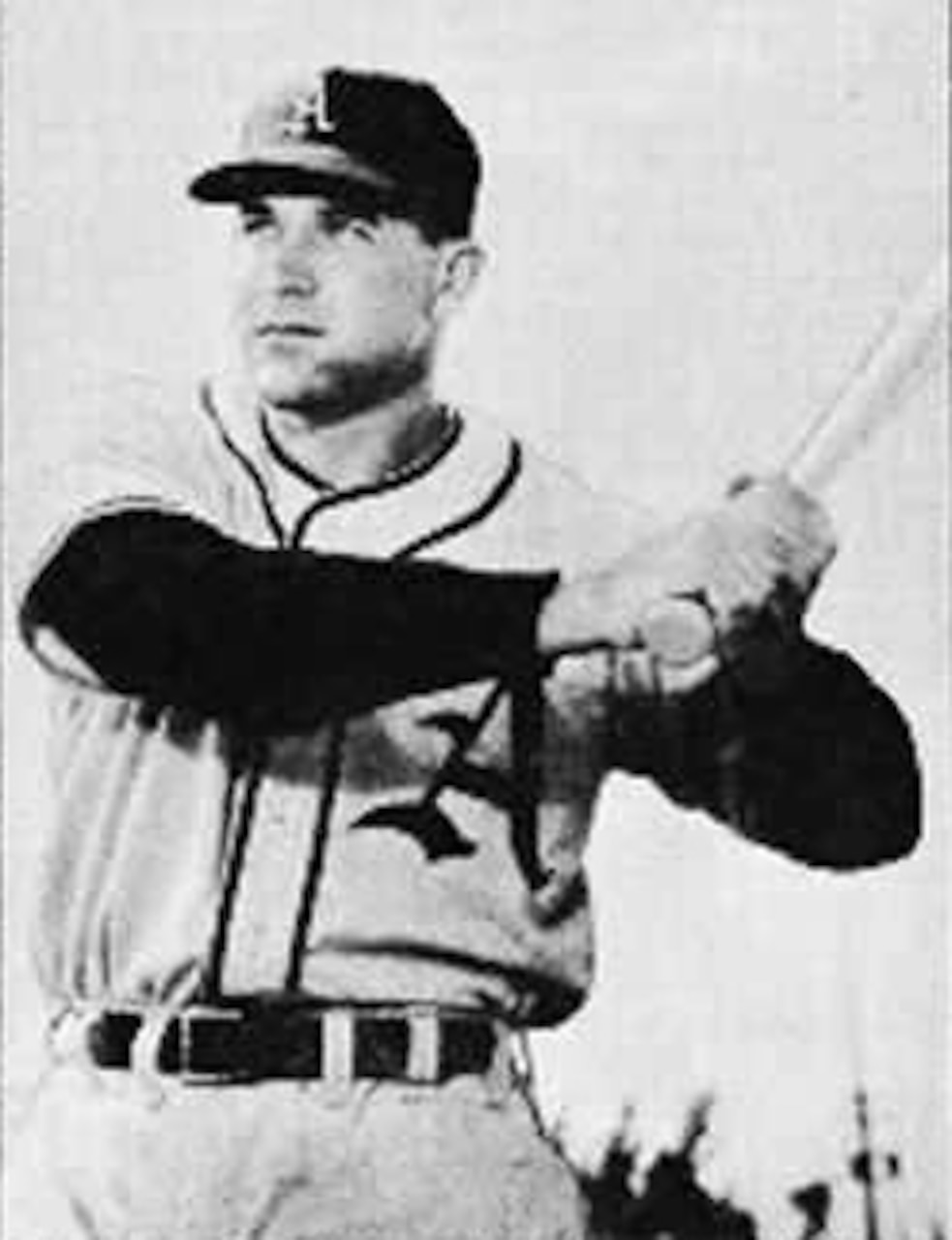 A baseball player holds up his bat as he poses for a photo.