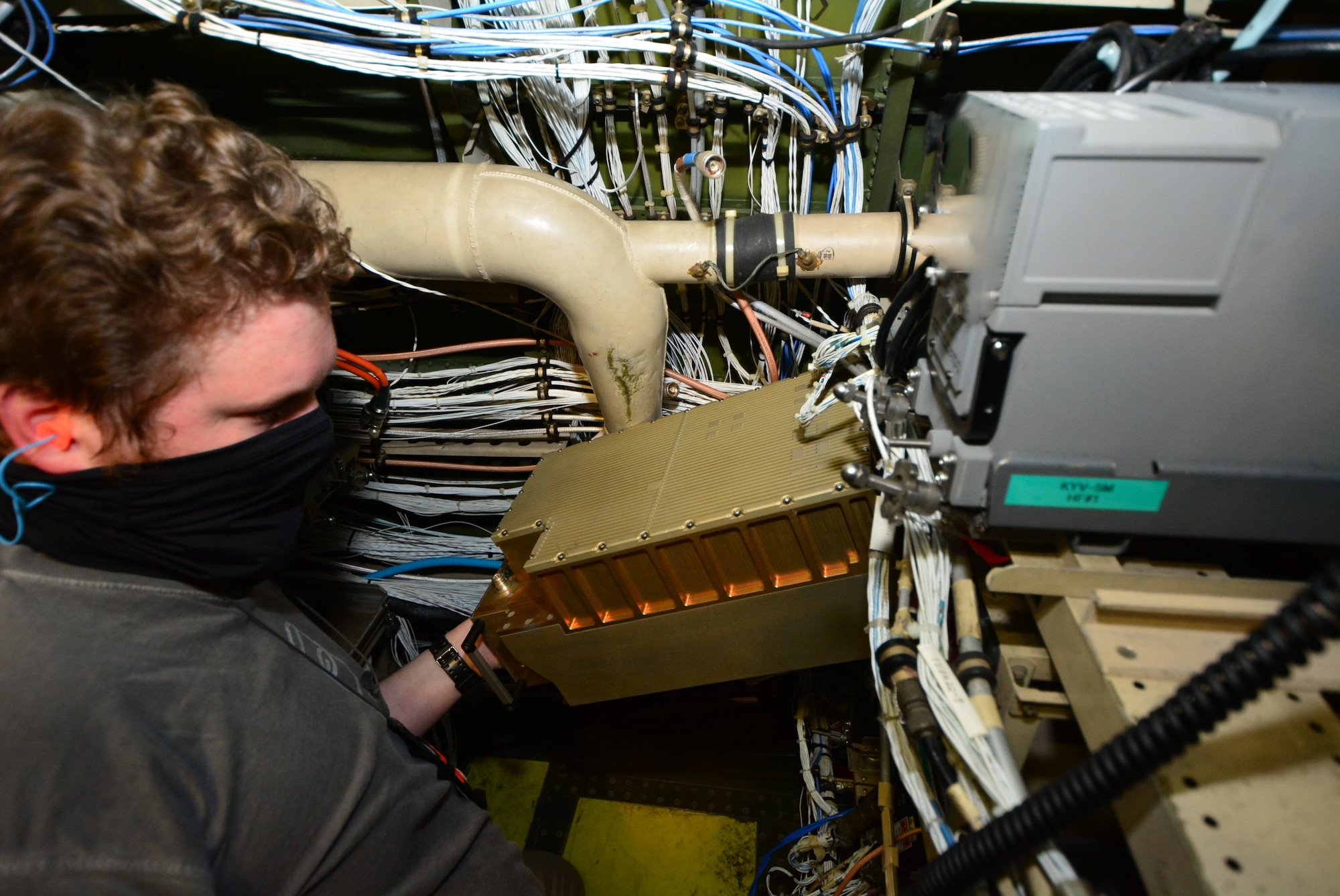 Photo shows man installing hardware surrounded by equipment and wires.
