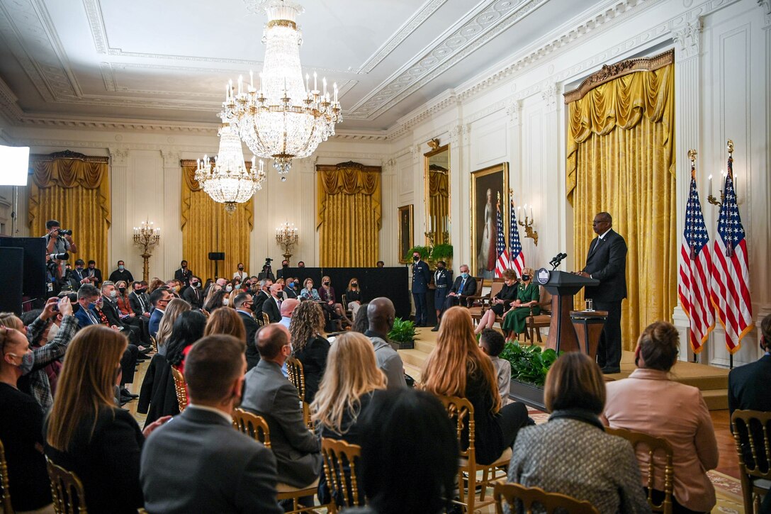 Secretary of Defense Lloyd J. Austin III speaks at lectern to seated audience.