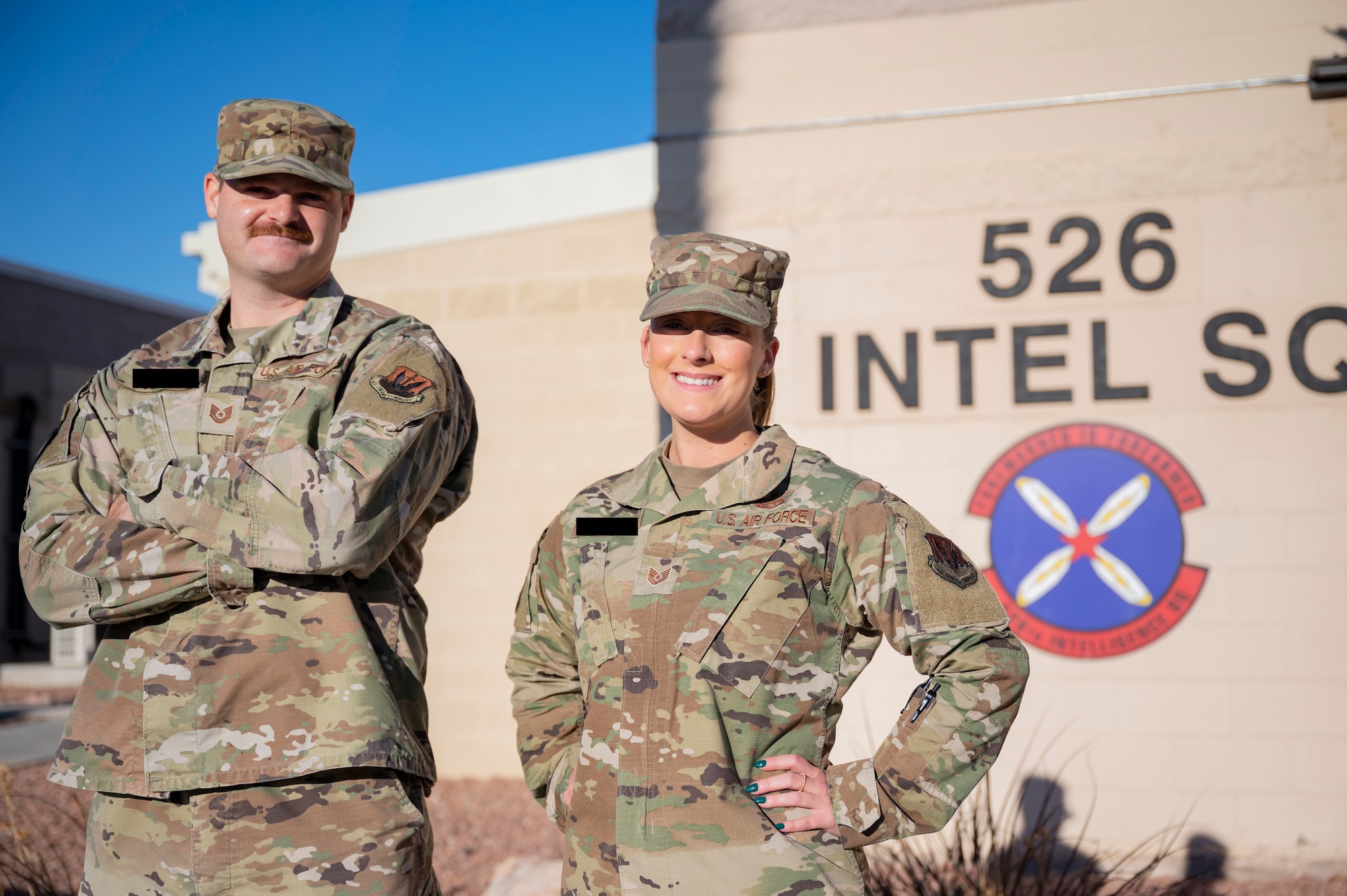 Two individuals pose in front of their building.