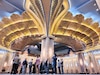 people look up at the gold embelished ceiling of the Grand Mosque.